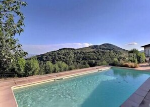 A swimming pool with a mountain backdrop, surrounded by greenery and a clear sky. - The Vault of the Stars overlooks the Monts d’Ardèche (Genestelle)