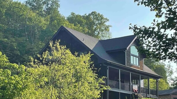 Una casa a due piani con un ampio portico e un'enorme finestra da soffitta.