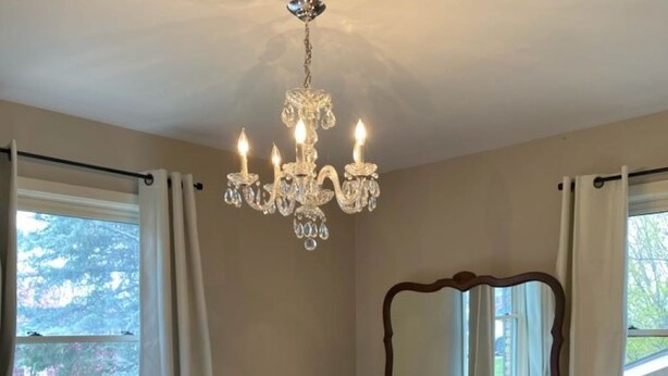 A bedroom with a large bed, a wooden dresser, a mirror, and a chandelier. - Four Bedroom Bellevue Beauty (Bellevue)