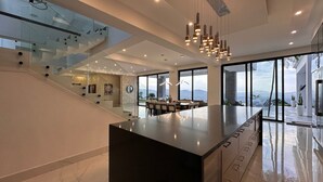 Een moderne keuken met een groot eiland, een glazen trap en uitzicht op de bergen.