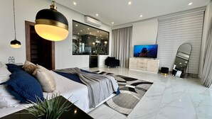 Een moderne slaapkamer met een groot bed, een televisie en een spiegel.