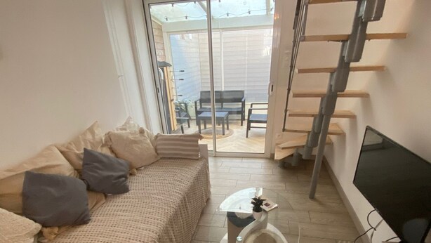 A living room with a sofa, a glass coffee table, a TV, and a staircase.