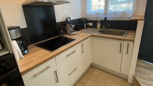 A compact kitchen with a stove, sink, and a window with curtains.