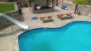 Una piscina con tobogán, mesas de picnic y zona de barbacoa.