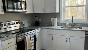 Una cocina moderna con gabinetes blancos, electrodomésticos de acero inoxidable, un tapete estampado y una ventana que proporciona luz natural.