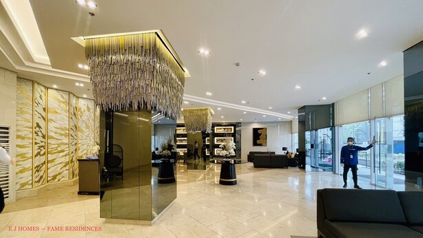A spacious lobby with a modern chandelier, a reception desk, and a large window offering a view of the outside.