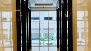 A modern hallway with reflective floors and glass doors leading to a building.