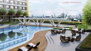 A modern outdoor pool area with lounge chairs and a city skyline view.