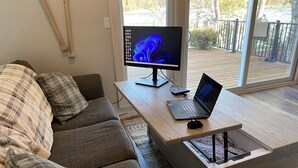 Un salon avec un canapé, une table basse en bois, un ordinateur portable et un écran.