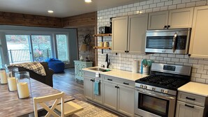 Une cuisine moderne dotée d’appareils électroménagers en acier inoxydable, de meubles blancs et d’un plancher en bois.