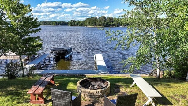 Une terrasse au bord du lac, avec un foyer, deux chaises et une table de pique-nique.