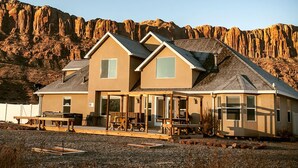 Une maison à deux étages dotée d’un grand porche et surplombant un paysage montagneux.