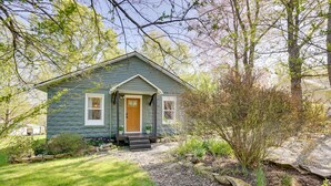 A small, single-story house with a front porch, a wooden door, and a small garden area with plants and a stone pathway. - Mid-Century Modern Fayetteville Home Close to Town (Fayetteville)