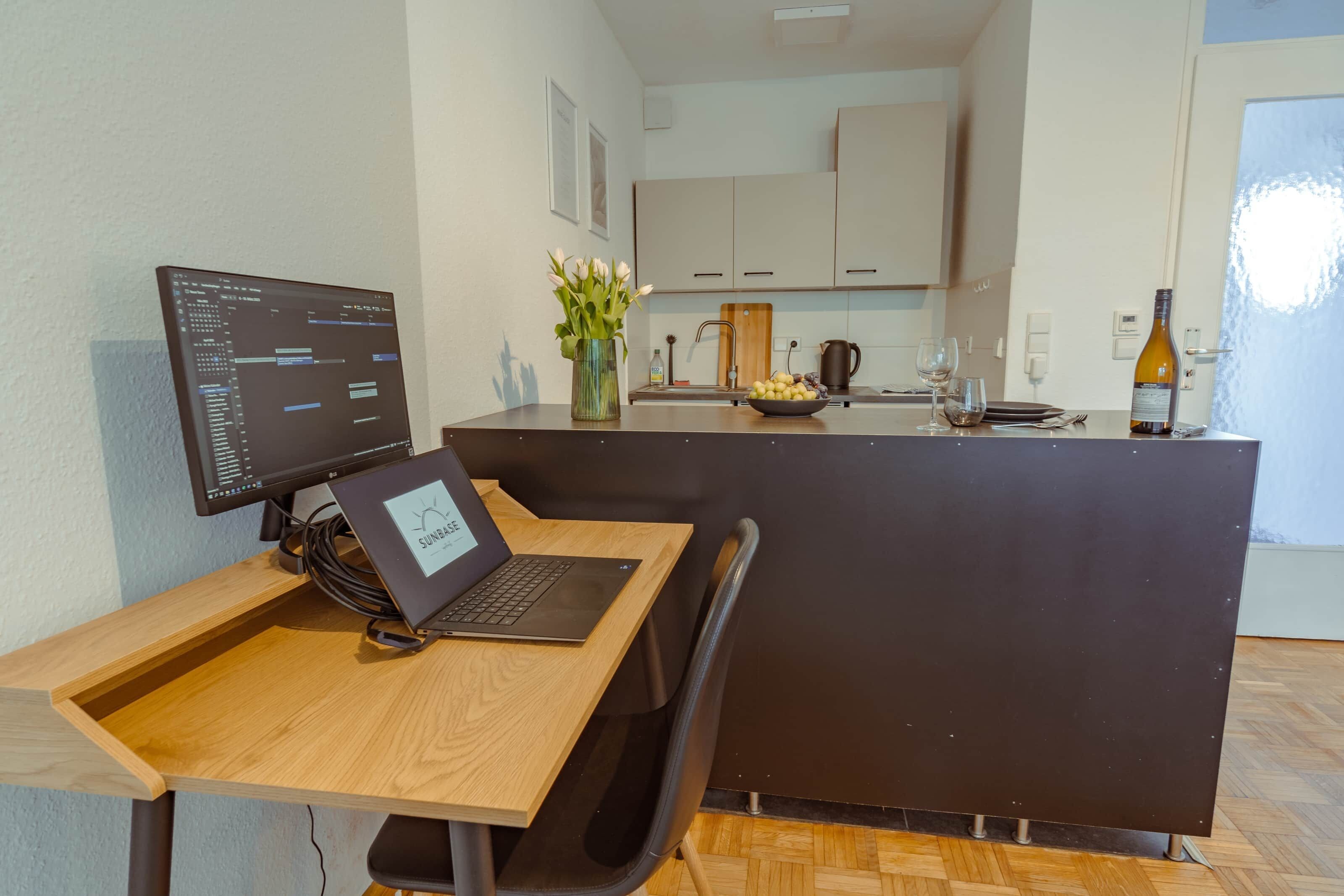Eine moderne Küche mit Essbereich, einem Computerarbeitsplatz und Blick ins Freie.