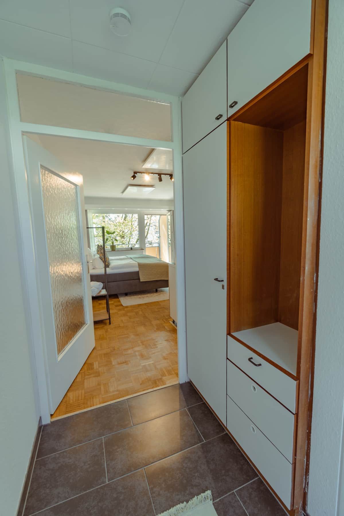 Un pasillo con una cama, un armario y una puerta que da a otra habitación.