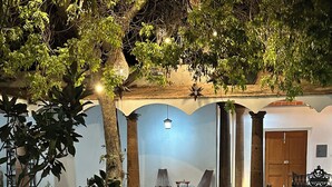 A courtyard with a fire pit, outdoor seating, and a covered area with columns and a door.