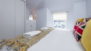 Un dormitorio con cama, ventana con vistas, armario y lámpara.