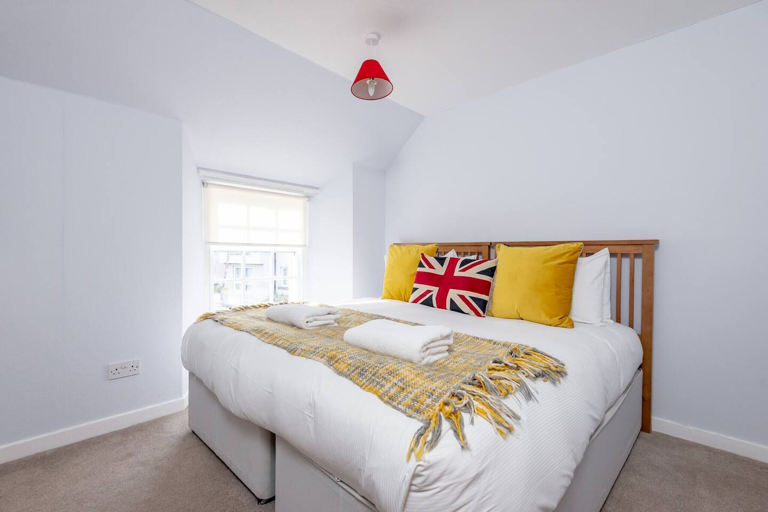 A bedroom with a bed, a window, and a red ceiling light.