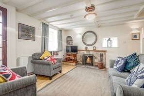 A living room with a fireplace, a television, and a framed picture on the wall. - Quirky Cottage (St Andrews)