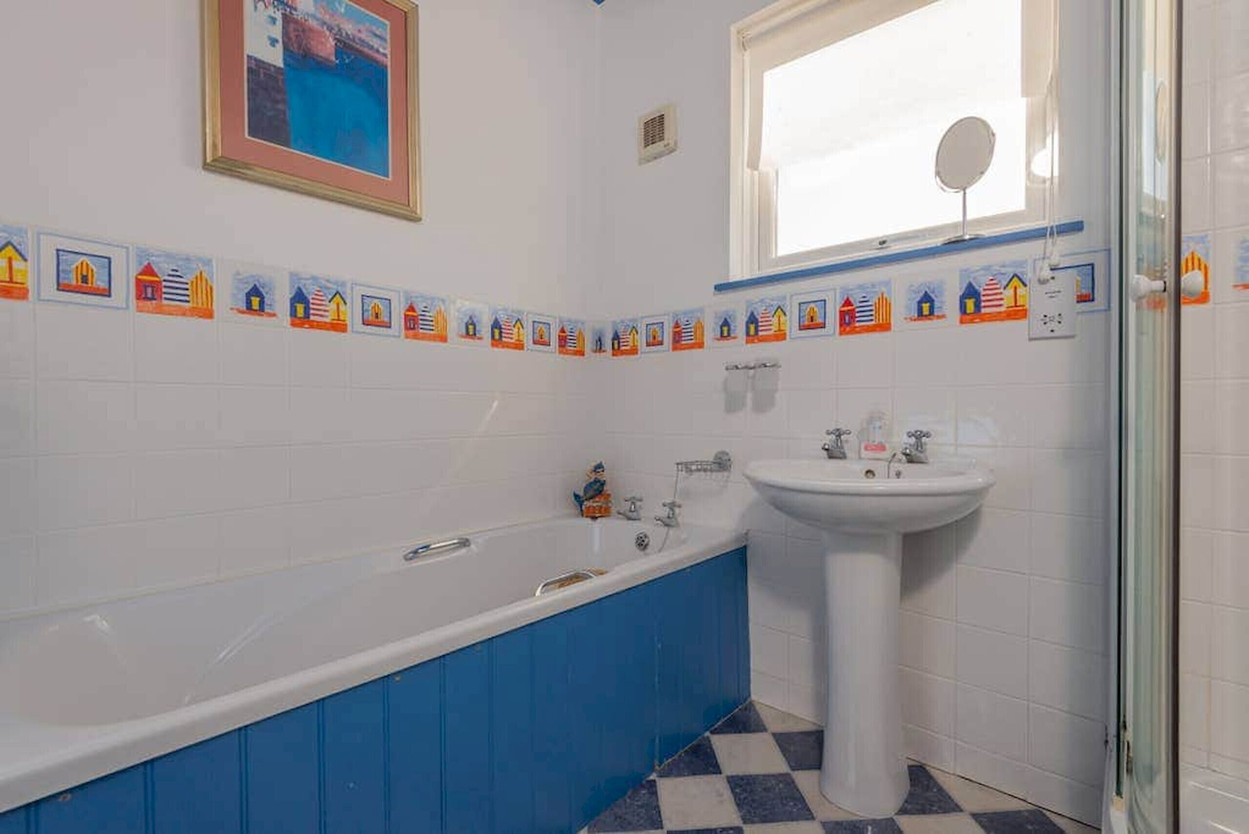 Een badkamer met een bad, wastafel en een raam.