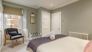 Une chambre à coucher avec un lit, une chaise, un radiateur et une fenêtre avec un store.