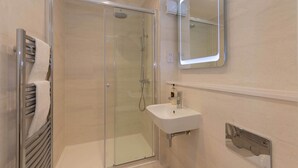 A modern bathroom with a glass-enclosed shower, a white sink, and a mirror above it. - 30C The Scores (St Andrews)