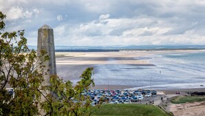 A coastal view with a parking lot, a tall monument, and a beach. - Gillespie Apartments | Spectacular Penthouse (St Andrews)