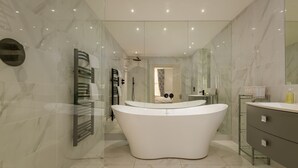 A modern bathroom with a freestanding bathtub, a glass shower enclosure, and a vanity with a mirror. - Gillespie Apartments | Golfer's Dream (St Andrews)