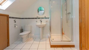 A modern bathroom with a glass-enclosed shower, a toilet, and a sink. - Dempster Lodge (St Andrews)