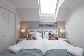 Un dormitorio con dos camas, un tragaluz y vistas al exterior.