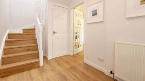 A staircase leading to a door, a white radiator, and framed pictures on the wall. - Abbey Villa (No 5) (St Andrews)