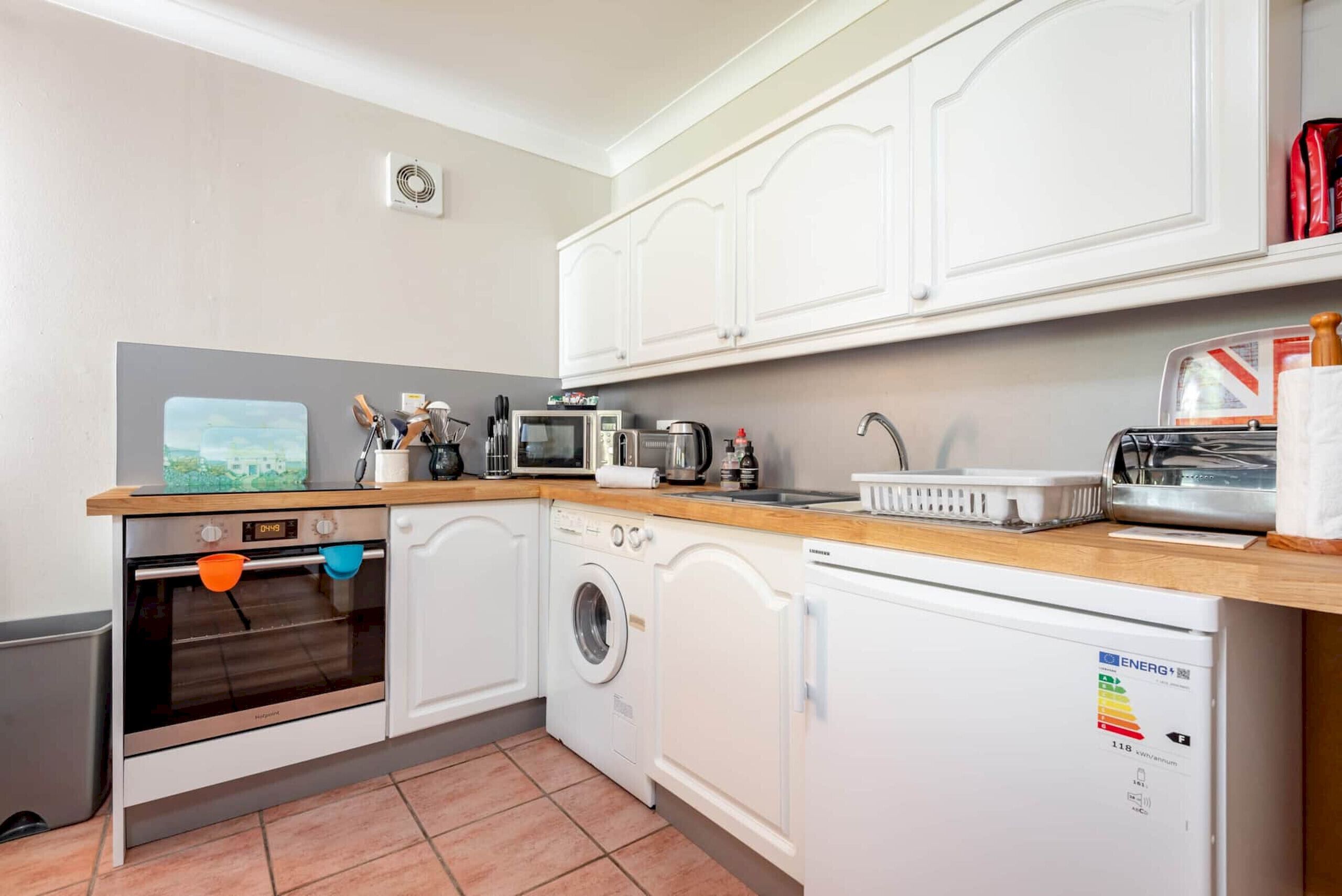 A compact kitchen with a microwave, toaster, sink, and a washing machine.