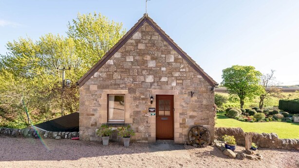 A small stone building with a pitched roof, a door, and a window. - Old Mill Cottage (Dunino)