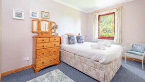 A bedroom with a bed, dresser, and a window with curtains. - Old Mill Cottage (Dunino)