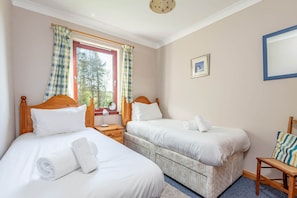 A bedroom with two beds, a window with curtains, a bedside table with a lamp, and a framed picture on the wall. - Old Mill Cottage (Dunino)