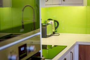 Une cuisine avec un revêtement mural vert, un robinet en acier inoxydable et un grille-pain.
