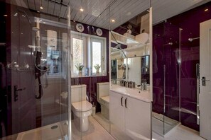Une salle de bain moderne avec une douche à parois de verre, des toilettes blanches et un meuble-lavabo avec un miroir.