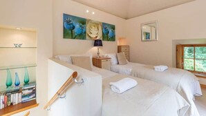 A bedroom with two beds, a bookshelf, and artwork on the wall. - The Bothy | Feddinch (St Andrews)