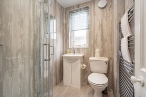 A compact bathroom with a glass shower enclosure, a sink, and a toilet. - Boase Avenue (No 26) | St Andrews (St Andrews)