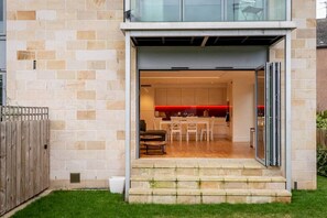 A modern house with a glass door leading to a kitchen and dining area.