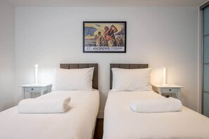 A hotel room with two beds, white bedding, and a framed picture on the wall.