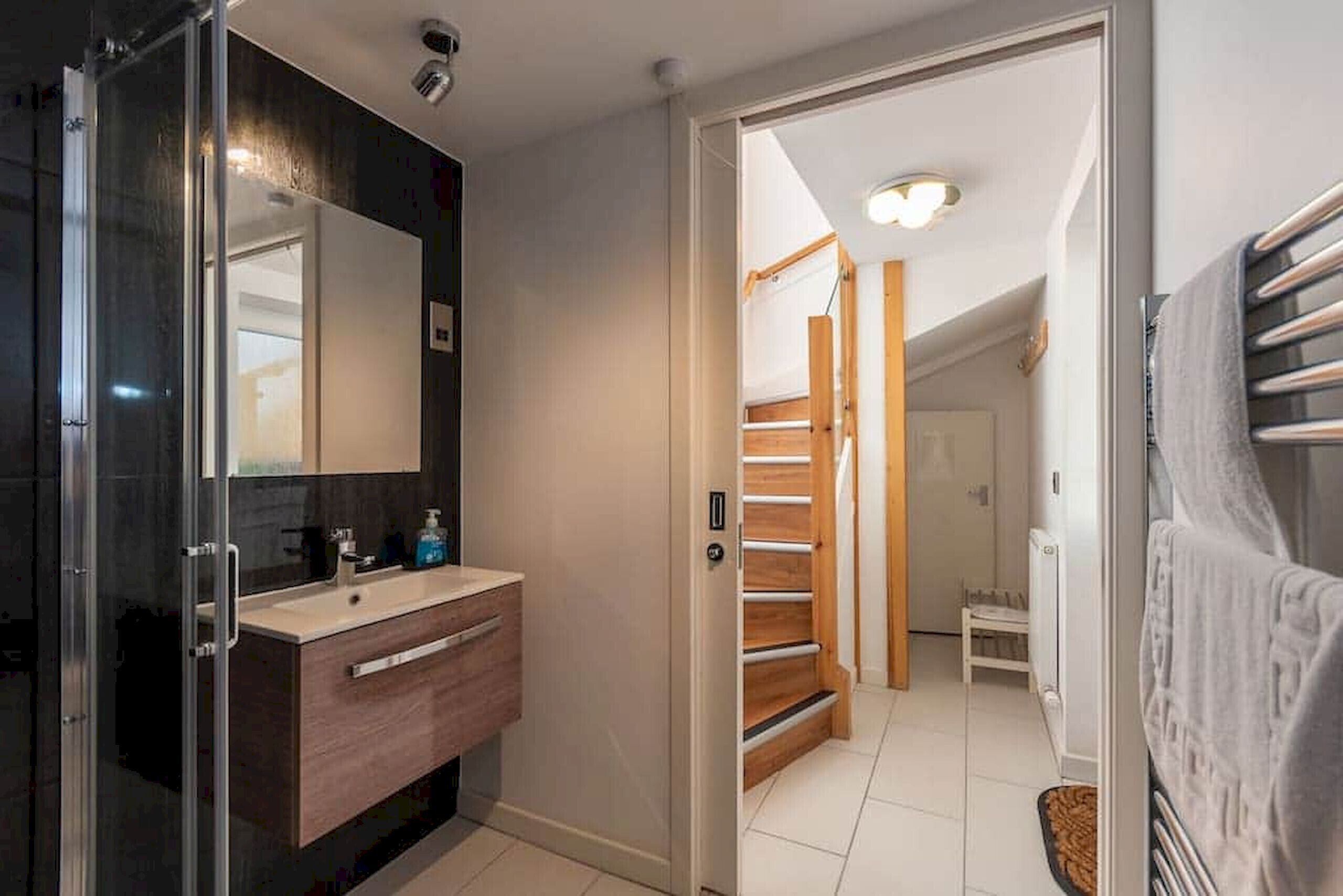 A modern bathroom with a glass shower enclosure, a wooden vanity, and a large mirror.