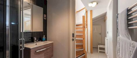 A modern bathroom with a glass shower enclosure, a wooden vanity, and a large mirror.