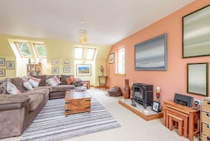 A cozy living room with a sofa, coffee table, fireplace, and artwork on the walls. - Muir Park Cottage (Grange)
