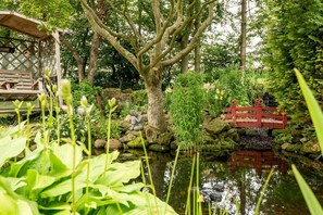 A serene garden with a pond, a wooden bridge, and a gazebo. - Muir Park Cottage (Grange)
