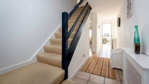 Eine Treppe mit beigefarbenem Teppich und einem schwarzen Geländer, das zu einer Tür führt.