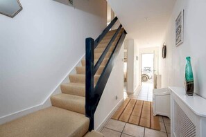 Stairs lead to an upper level, featuring a console table and a framed picture.