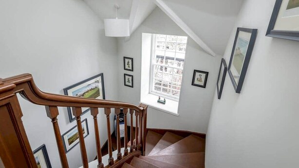 A staircase with wooden railings leading to a landing with a large window.
