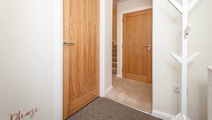 Un couloir avec des portes en bois et un porte-manteau blanc.