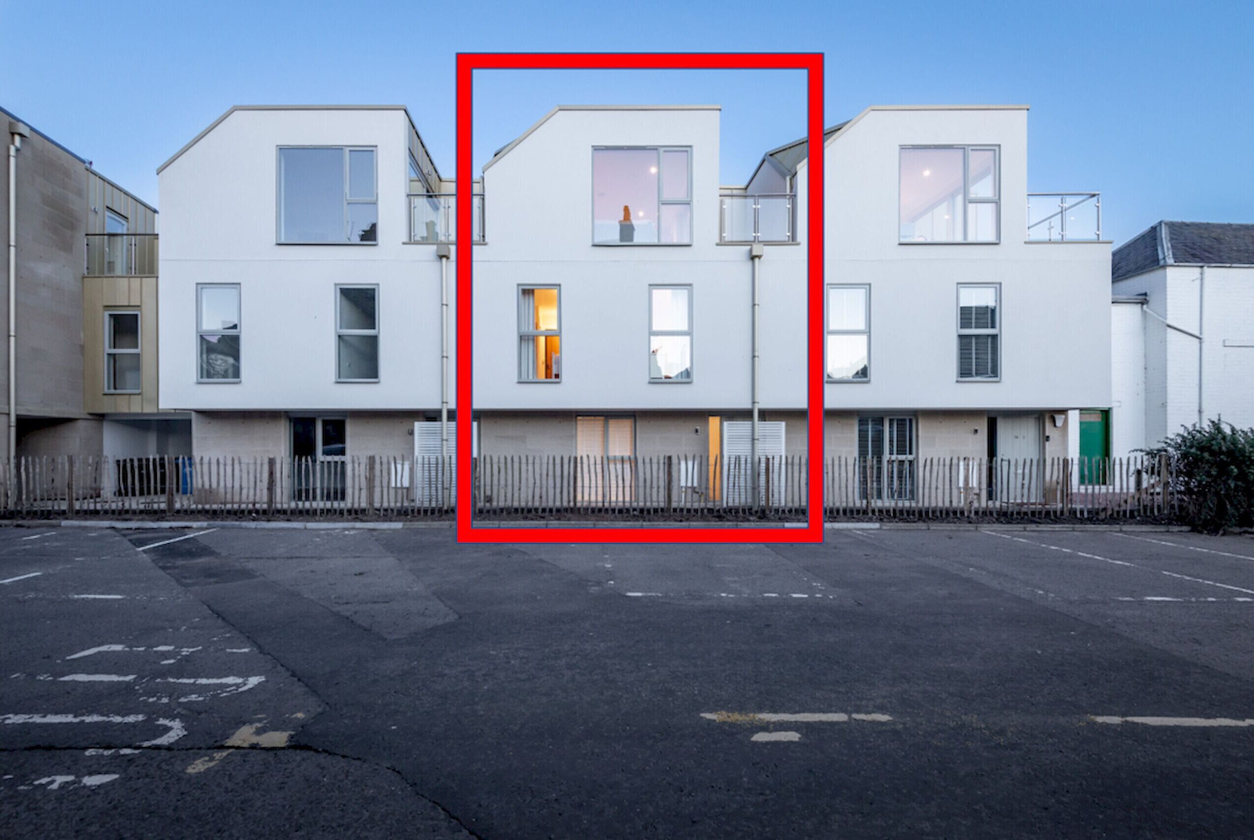 Une rangée d’immeubles d’appartements modernes, blancs, dotés de nombreuses fenêtres et de balcons.